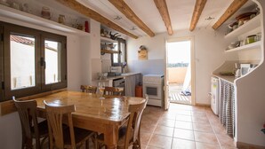 Una cocina amplia con vigas de madera, una mesa de comedor con sillas y vistas al exterior.