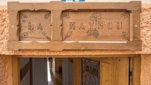 Un letrero de madera con el nombre 'LA MAYOU' y decoraciones de hojas y flores.