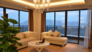 A spacious living room with two sofas, a round coffee table, and a large window offering a mountain view. - Wyndham Garden Lingshui (Lingshui)