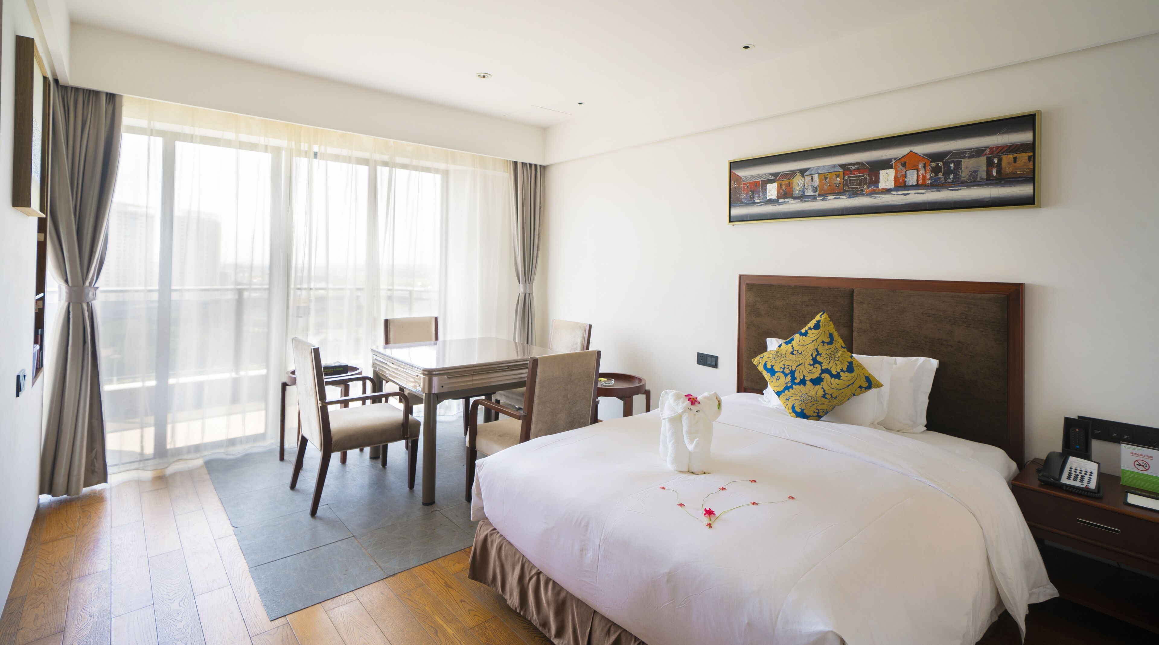Un cuarto de hotel con una cama grande, un escritorio con sillas, un cuadro en la pared y vistas por la ventana.