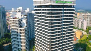 A modern high-rise building with a rooftop garden and a circular structure at its base. - Wyndham Garden Lingshui (Lingshui)