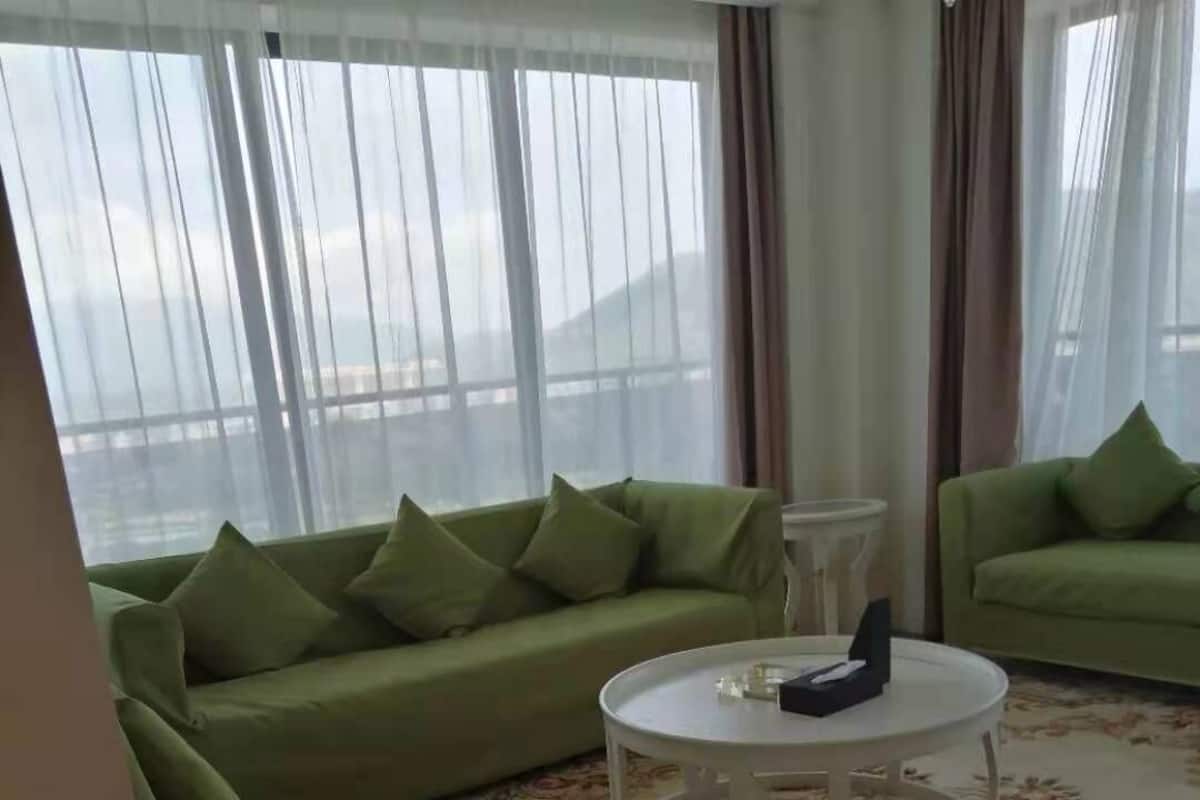 Ein Wohnzimmer mit zwei grünen Sofas, einem weißen Couchtisch und einem Teppich mit floralem Muster.