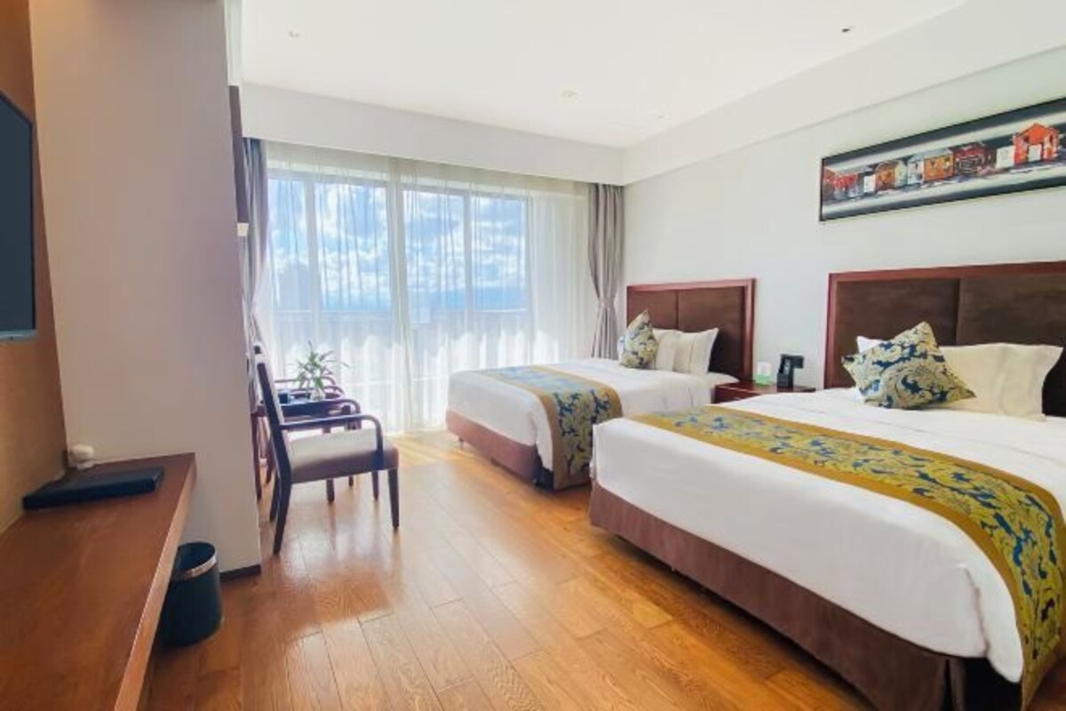 Une chambre d’hôtel avec deux lits, un bureau et une chaise.