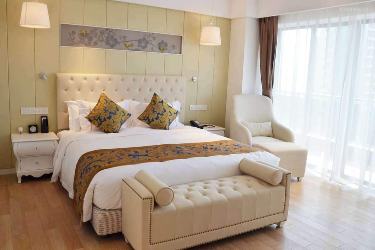 Ein Hotelzimmer mit einem großen Bett, einem Sessel, einem Nachttisch und einer Lampe.
