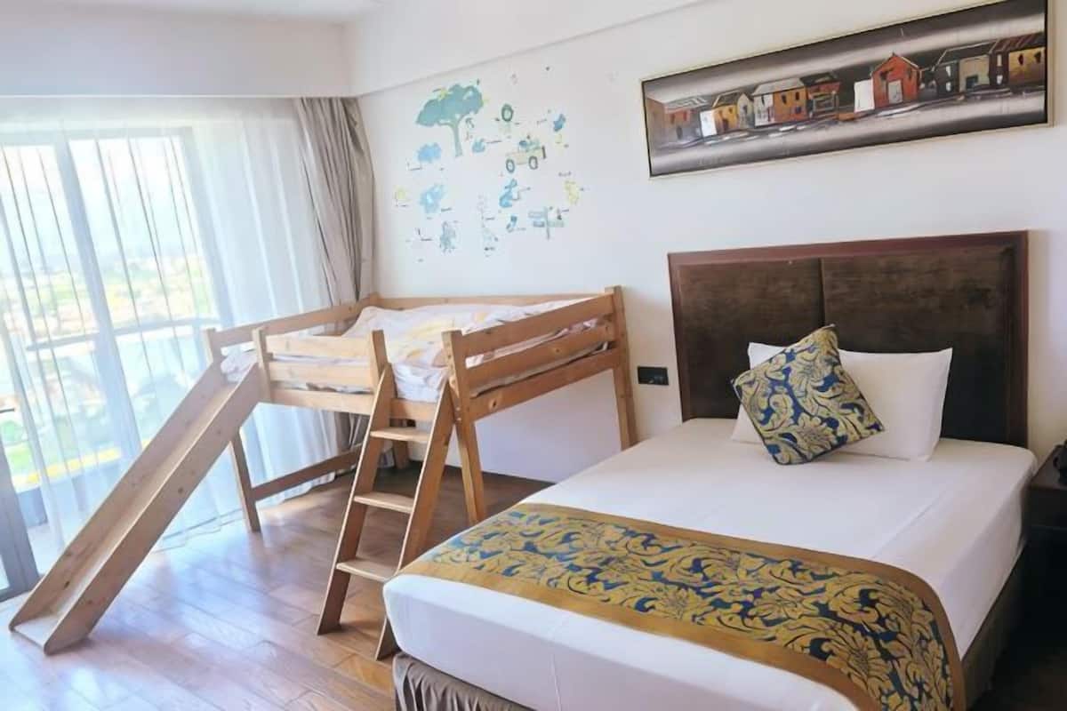 Ein Schlafzimmer mit einem Etagenbett, einem Schreibtisch und einem Bett mit einem gemusterten Bettüberwurf.