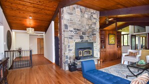 A spacious living room with a stone fireplace, wooden ceiling, and a blue sofa.