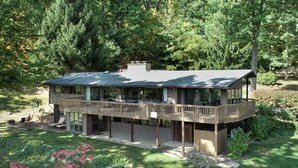 A two-story house with a balcony, surrounded by a garden and trees.