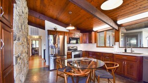 A kitchen with wooden cabinets, a stone wall, and a glass dining table with chairs.