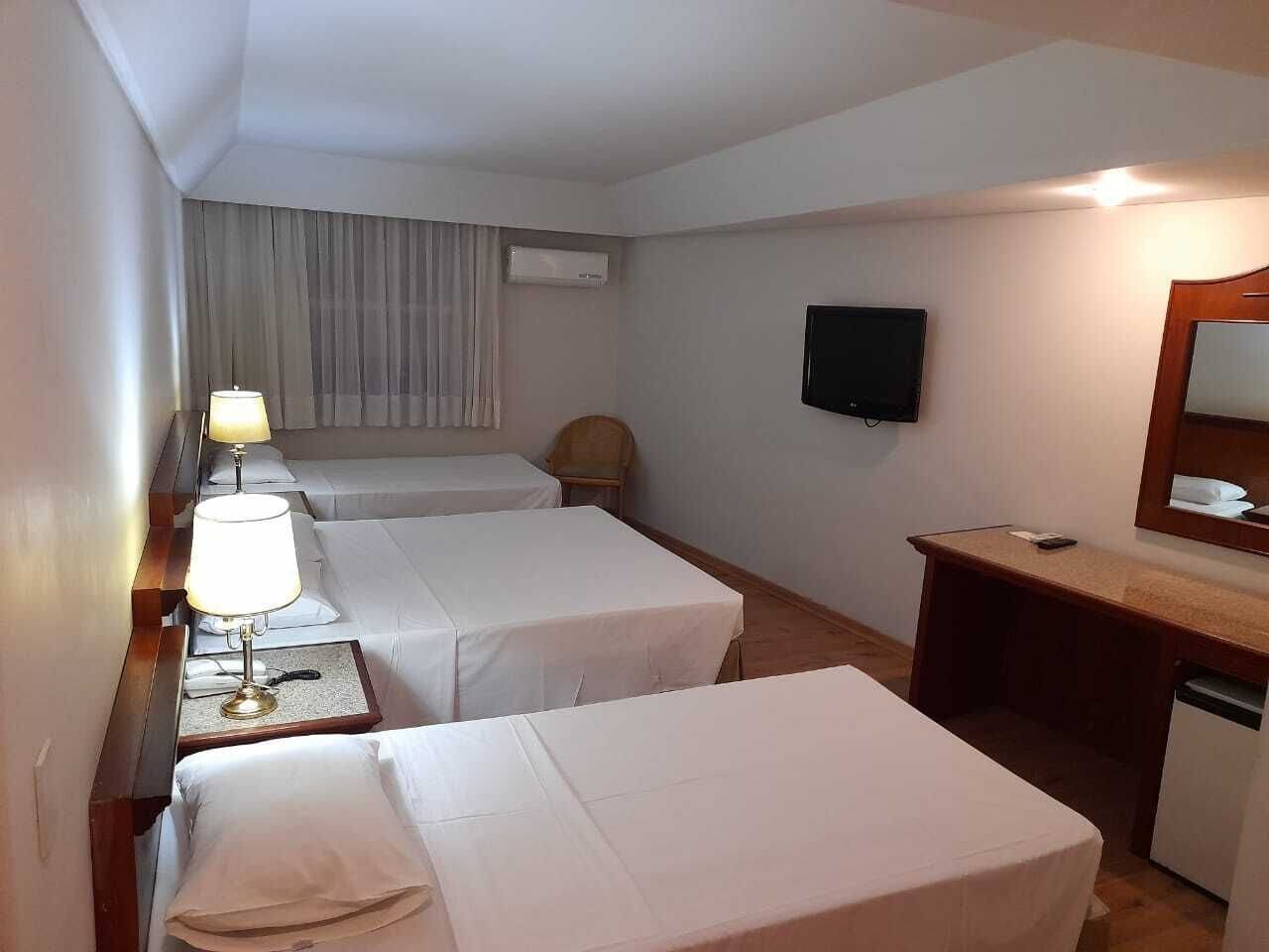 Hotellihuone, jossa on kaksi sänkyä, työpöytä, tuoli, televisio ja ilmastointilaite.