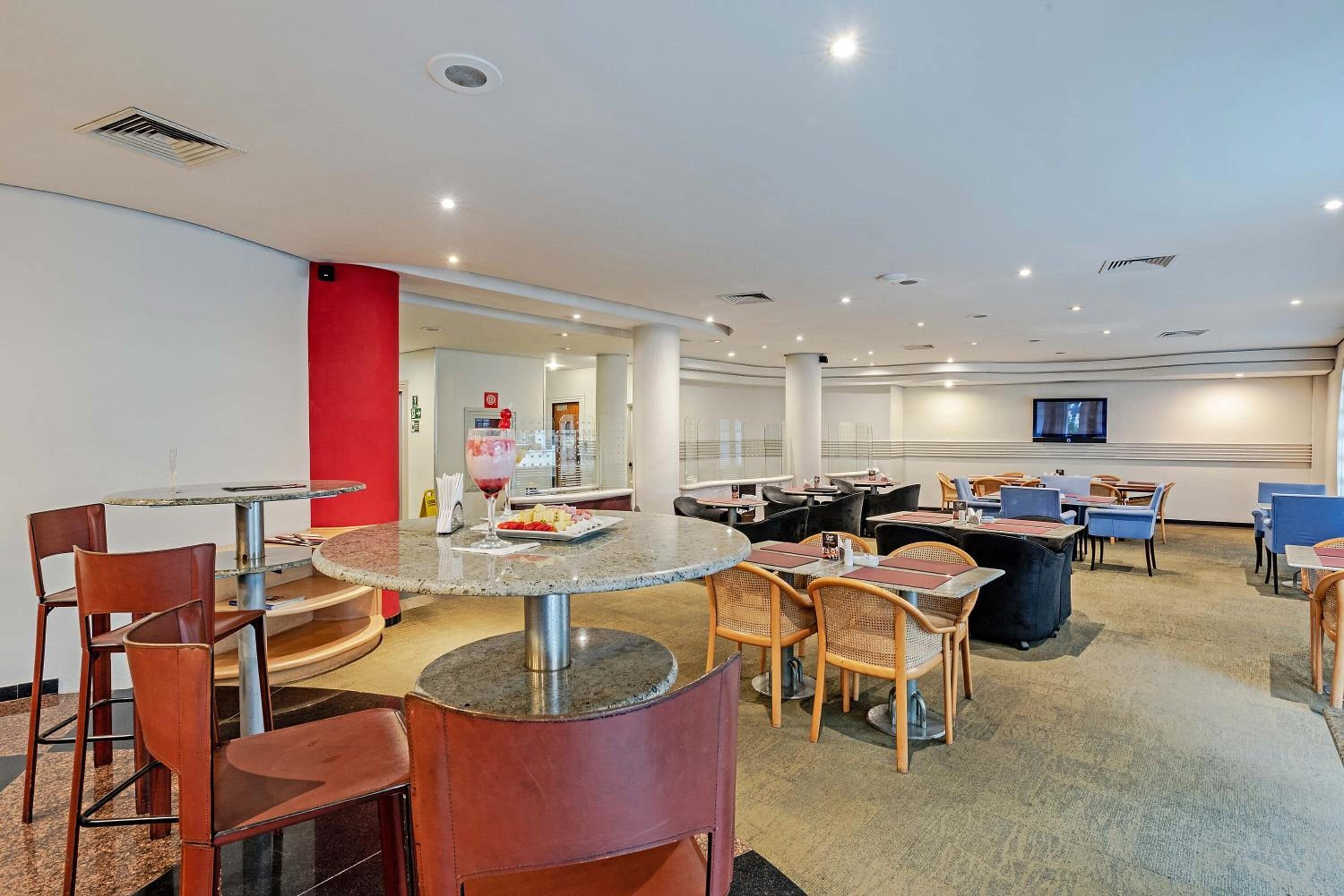Um lobby de hotel moderno com mesas redondas, cadeiras de couro e um bar.