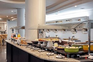 Disposição de buffet com diversos alimentos e utensílios.