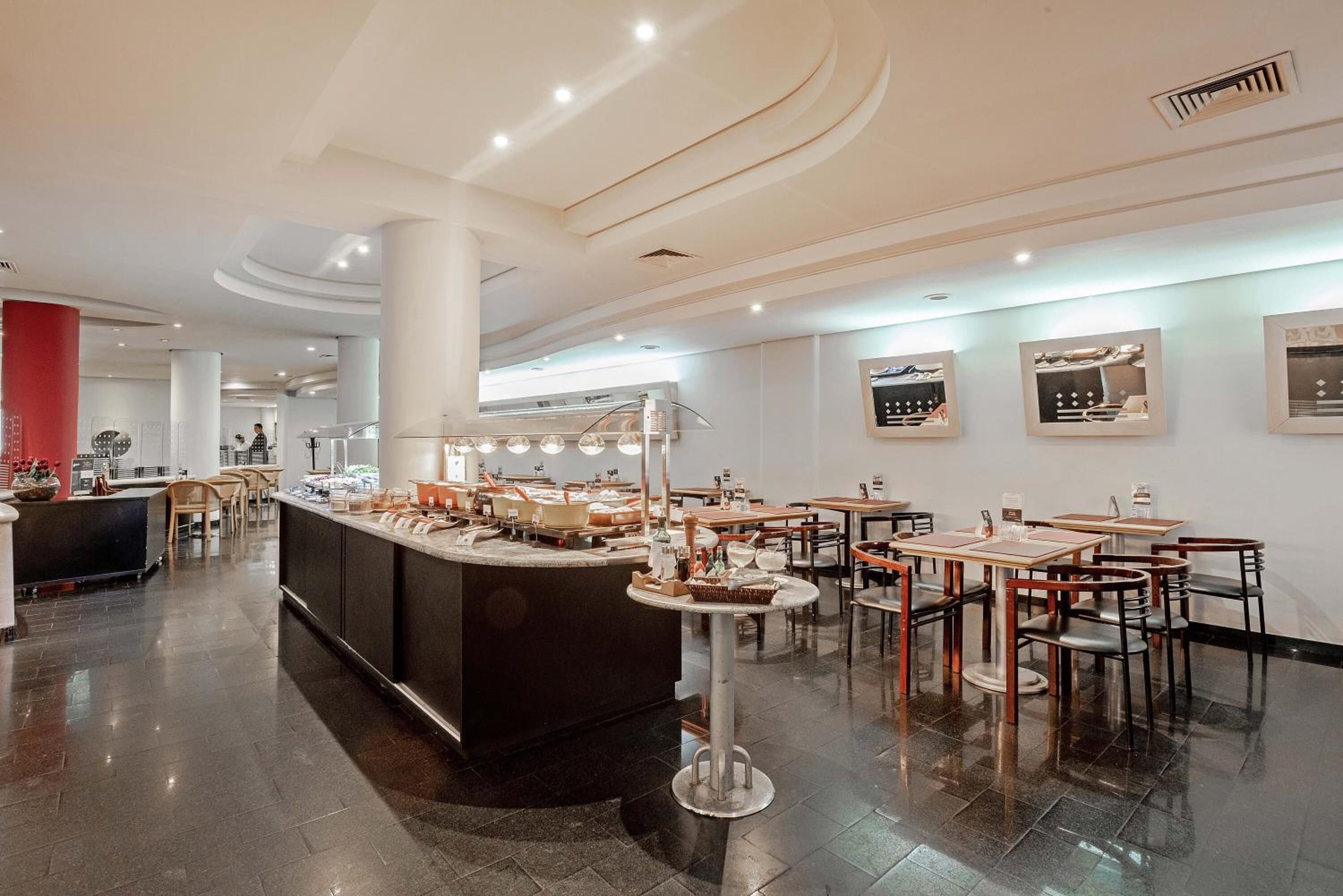 Um restaurante moderno com um balcão central, várias mesas e cadeiras.