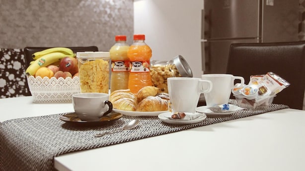 Una mesa con bollos, fruta, jugo y tazas de café para el desayuno.