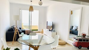 Ett modernt vardagsrum med ett matbord i glas, en soffa, en tv och en leksaksbil.