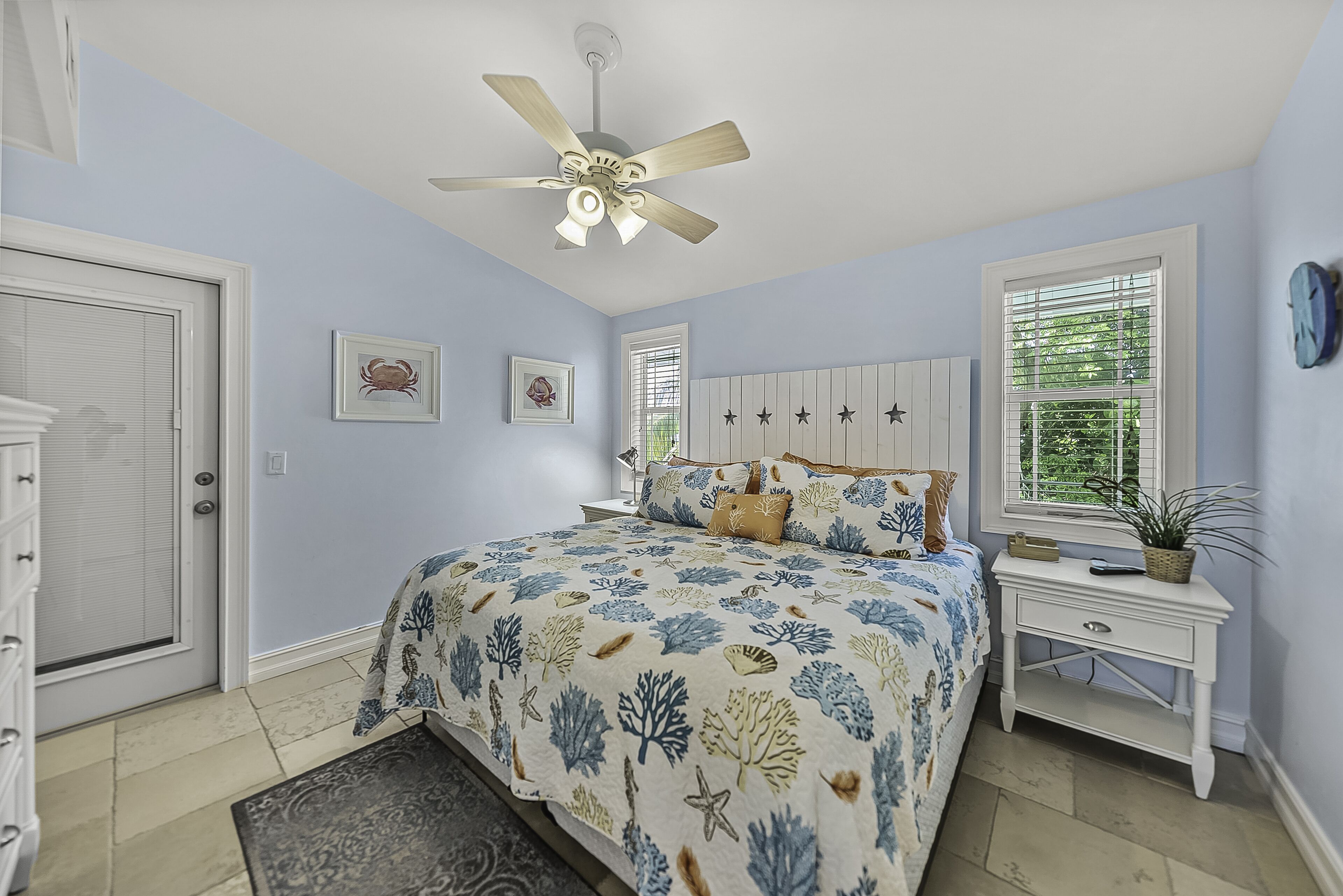A bedroom with a bed, a nightstand, a ceiling fan, and a window with blinds.
