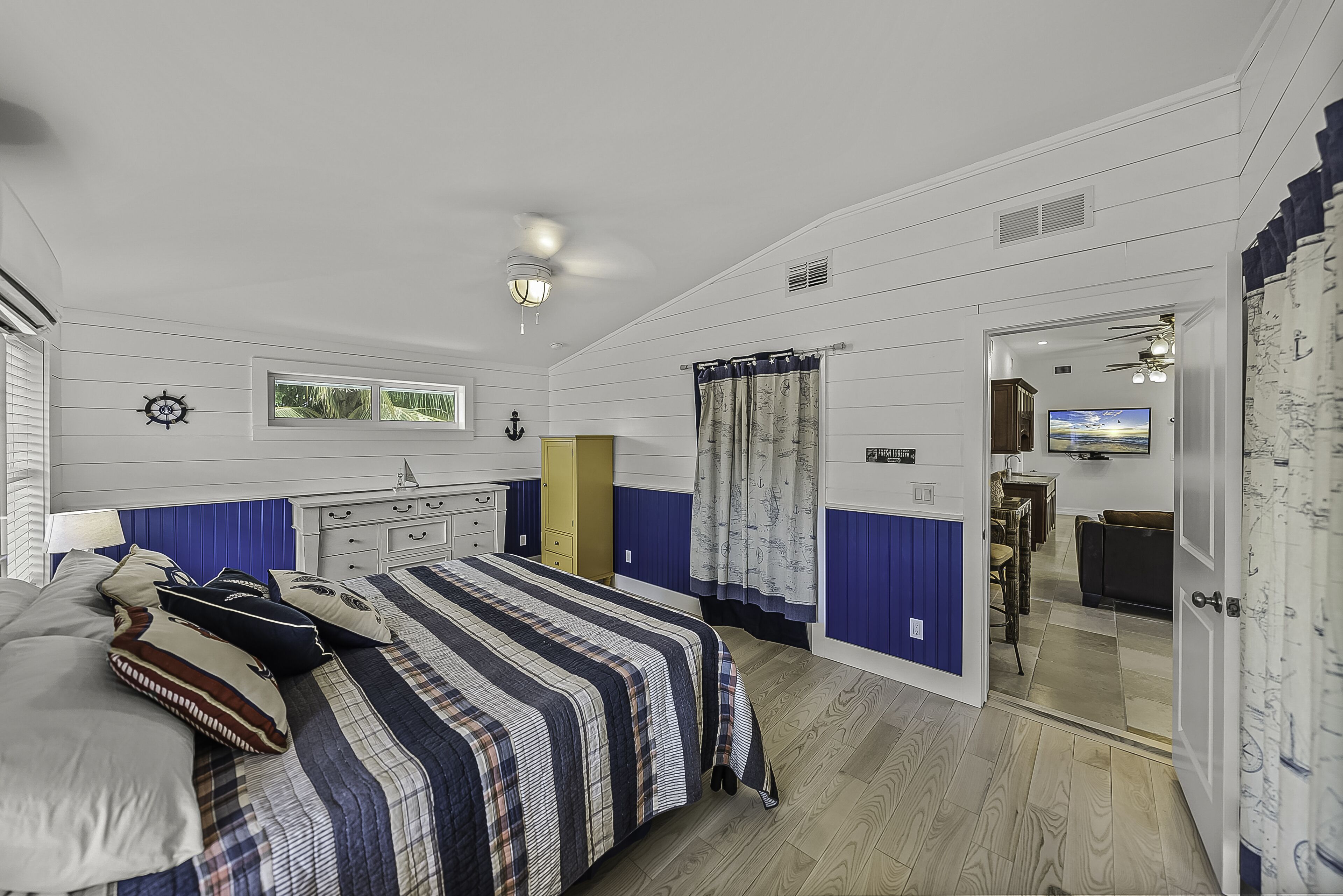Une chambre à coucher avec un lit, une commode et un téléviseur dans la pièce adjacente.