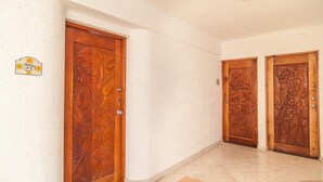 A hallway with two wooden doors with floral carvings, a white wall, and a tiled floor. - Private Terrace & Hammock Near Mamitas Beach (Playa del Carmen, Q.R.)