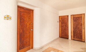 A hallway with two wooden doors with floral carvings, a white wall, and a tiled floor. - Private Terrace & Hammock Near Mamitas Beach (Playa del Carmen, Q.R.)