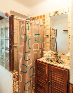 A bathroom with a shower curtain, a sink with a decorative basin, and a mirror above the sink.