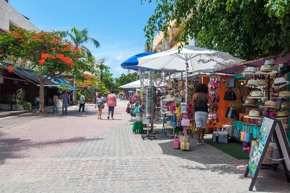 A pedestrian street with outdoor market stalls selling hats and bags.
