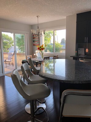 A modern kitchen with a large island, bar stools, and a dining area with chairs. - Place to relax from your busy life. (Wabamun)