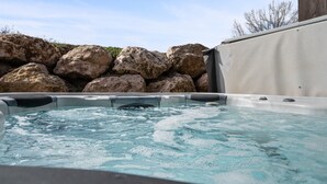 A hot tub with clear water, surrounded by large rocks and a wooden post. - Lakeside Escape LS 36B 2 BR |Pineview Res |Hot Tub (Huntsville)