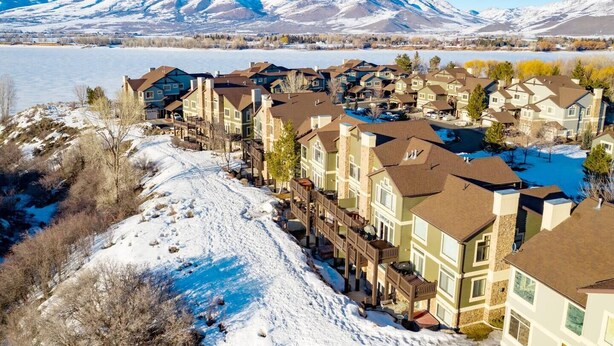 A residential area with multi-story houses, a snow-covered landscape, and mountains in the background. - Lakeside Escape LS 36B 2 BR |Pineview Res |Hot Tub (Huntsville)