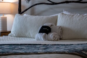 A bed with a quilted white mattress, a folded white towel, and a black tag with 'MOKO' on it. - Lakeside Escape LS 36B 2 BR |Pineview Res |Hot Tub (Huntsville)
