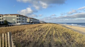 Un hôtel situé en bord de mer, doté de nombreux balcons et donnant sur une plage de sable.