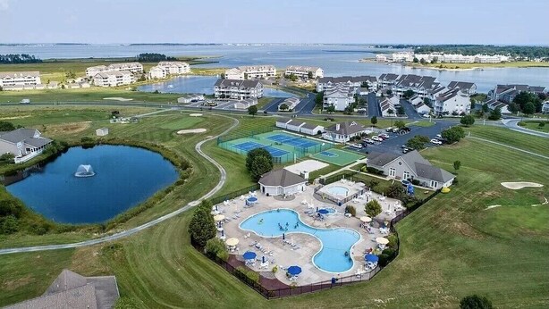 Vue aérienne d’un quartier résidentiel avec de nombreuses maisons, une grande piscine et un petit lac.