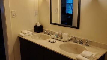 A bathroom with two sinks, a mirror, and a towel rack.