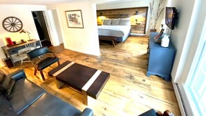 A compact room with a bed, a desk, and a seating area. - Luxury King Suite, Living Room w/sofa bed and jacuzzi tub (West Dover)