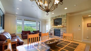 A cozy living room with a fireplace, a stone wall, and a large window overlooking greenery.