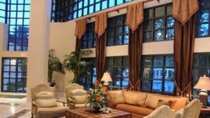 A spacious lobby with a high ceiling, large windows, and a seating area with a sofa and armchairs. - Luxury and privacy next to Disney  (Kissimmee)