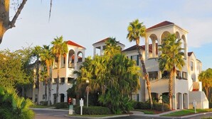 A large, white building with arched windows and a red roof, surrounded by palm trees and greenery. - Luxury and privacy next to Disney  (Kissimmee)