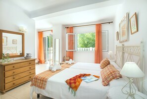 Een hotelkamer met twee bedden, een kaptafel, een spiegel en een raam met gordijnen.