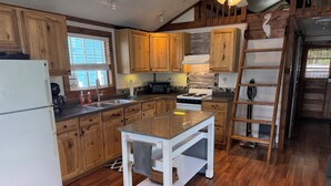 A kitchen with wooden cabinets, a white refrigerator, a stove, and a wooden ladder. - Sunset Lover's Dream! Lakefront Cottage on Otisco! (Marietta)