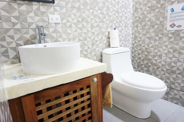 A bathroom with a white sink, toilet, and geometric-patterned tiles.