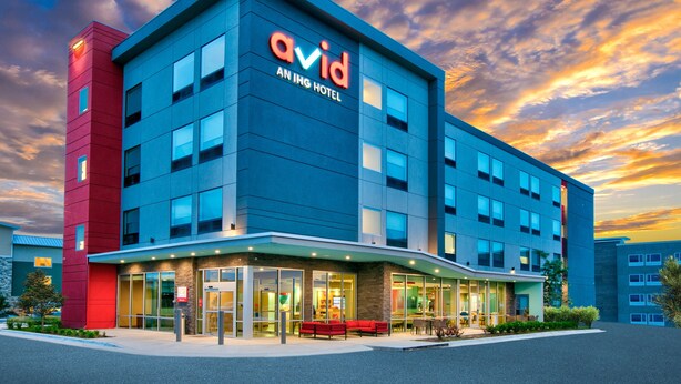 Un hôtel moderne, reconnaissable à son grand panneau « Avid », à ses larges fenêtres et à son hall d’entrée bien éclairé.