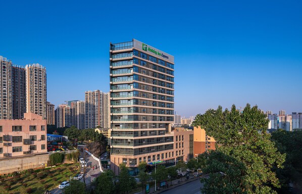 A multi-story hotel with a modern glass facade, located in an urban area with surrounding high-rise buildings. - Holiday Inn Express Changsha Shifu by IHG (Changsha)