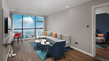 Una sala moderna con sofá, sillas, comedor y un amplio ventanal con vistas a la ciudad.
