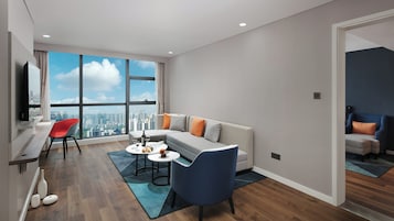 Sala de estar moderna com sofá, cadeiras, área de jantar e uma janela grande com vista para a cidade.