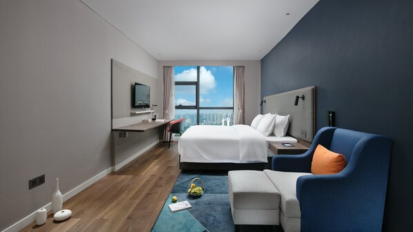 A modern hotel room with a large bed, a desk, a chair, and a view of the city. - Holiday Inn Express Hengyang High-Tech Zone by IHG (Hengyang)