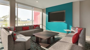 Een moderne woonkamer met een zithoek, een salontafel en een flatscreen televisie aan een muur in een blauwgroene kleur.