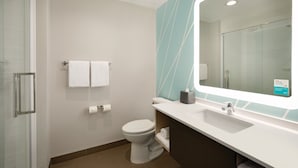 A modern bathroom with a glass shower enclosure, a white toilet, a sink with a mirror, and a towel rack.