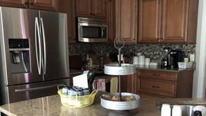 A kitchen with wooden cabinets, stainless steel appliances, granite countertops, and a central island with bar stools. - The Mulligan House in the heart of Pinehurst, NC. (Pinehurst)