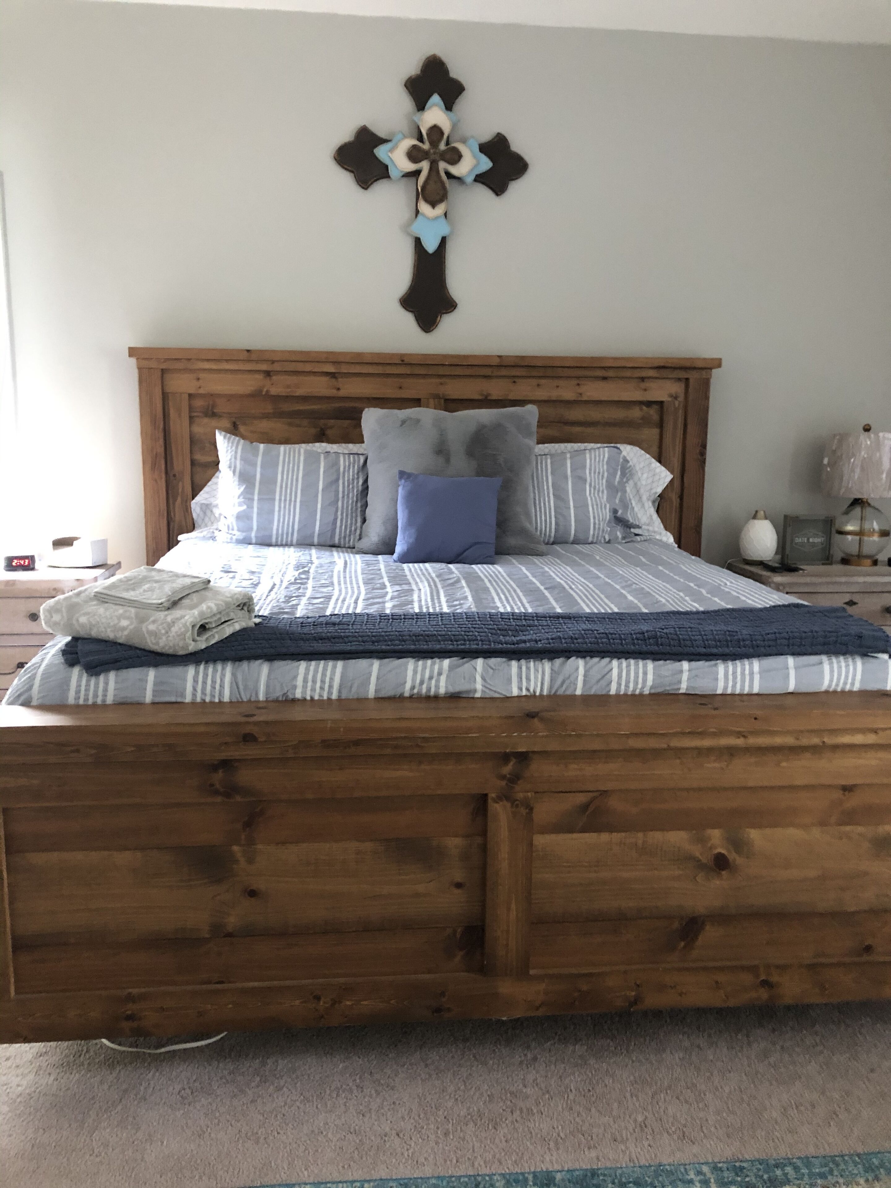 A wooden bed with a headboard, striped bedding, and a decorative wall piece above it.