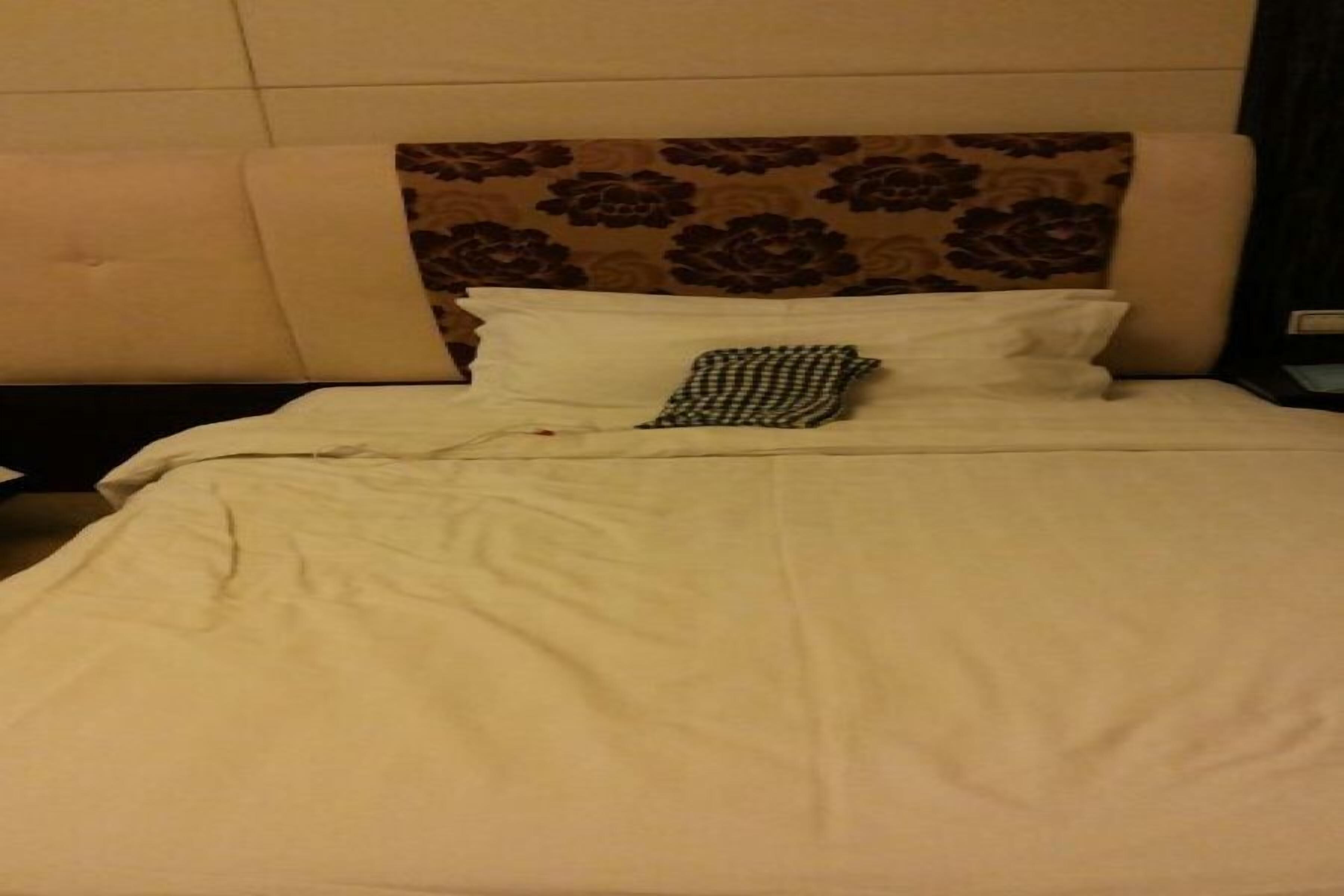 A bed with a white bedspread and two pillows, one plain and one patterned.