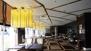Un hall de hotel espacioso con suelo de cuadros, muebles modernos y grandes ventanales que dejan entrar luz natural.