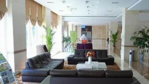 Un moderno vestíbulo de hotel con sofás de cuero, una mesa de centro y plantas en macetas.
